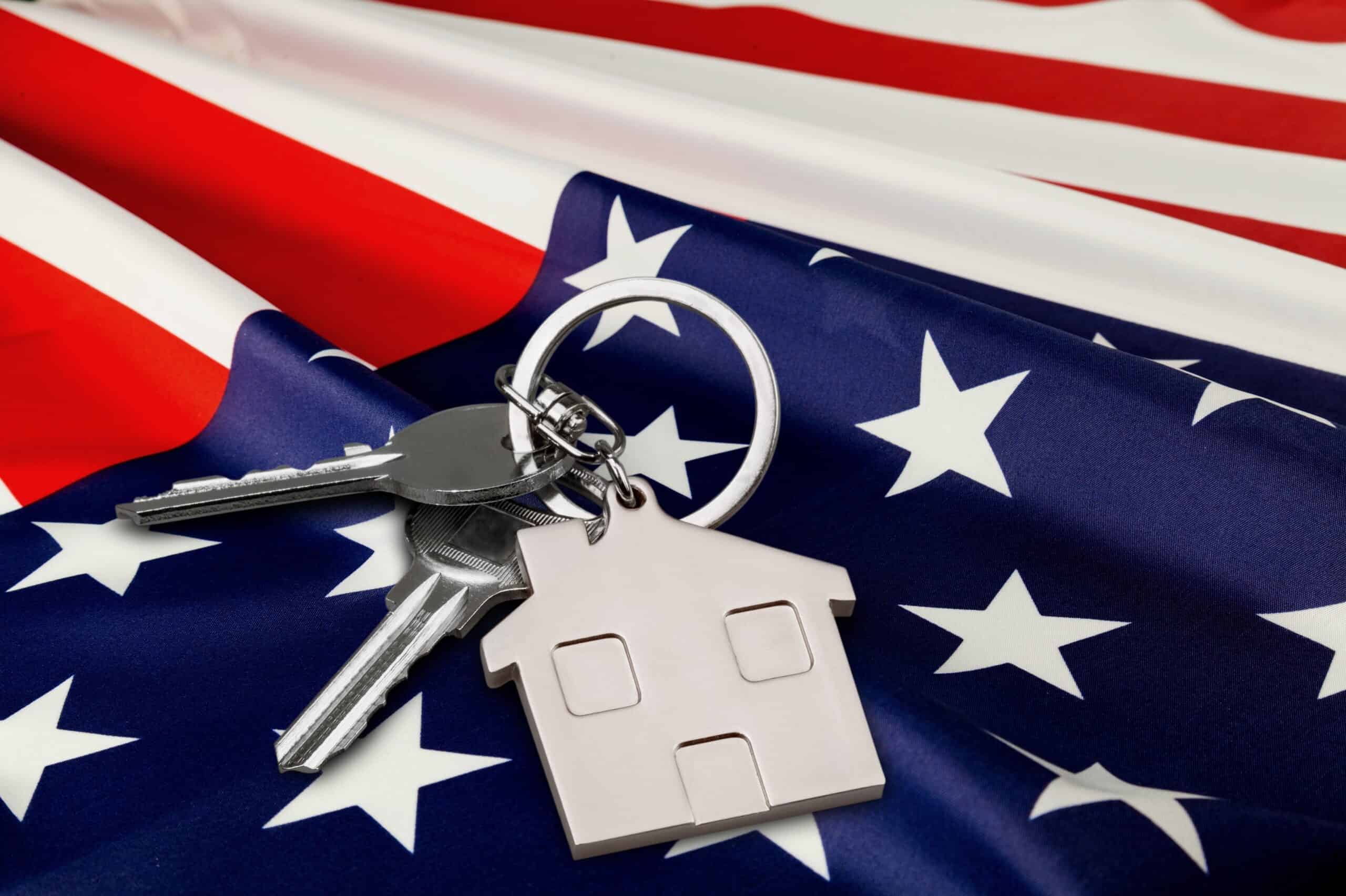 A house-shaped keychain and keys on an American flag, symbolizing VA home loans for U.S. military veterans.