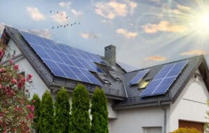 A modern house with solar panels on the roof, surrounded by greenery, under a bright sunlit sky, symbolizing renewable energy and home sustainability.