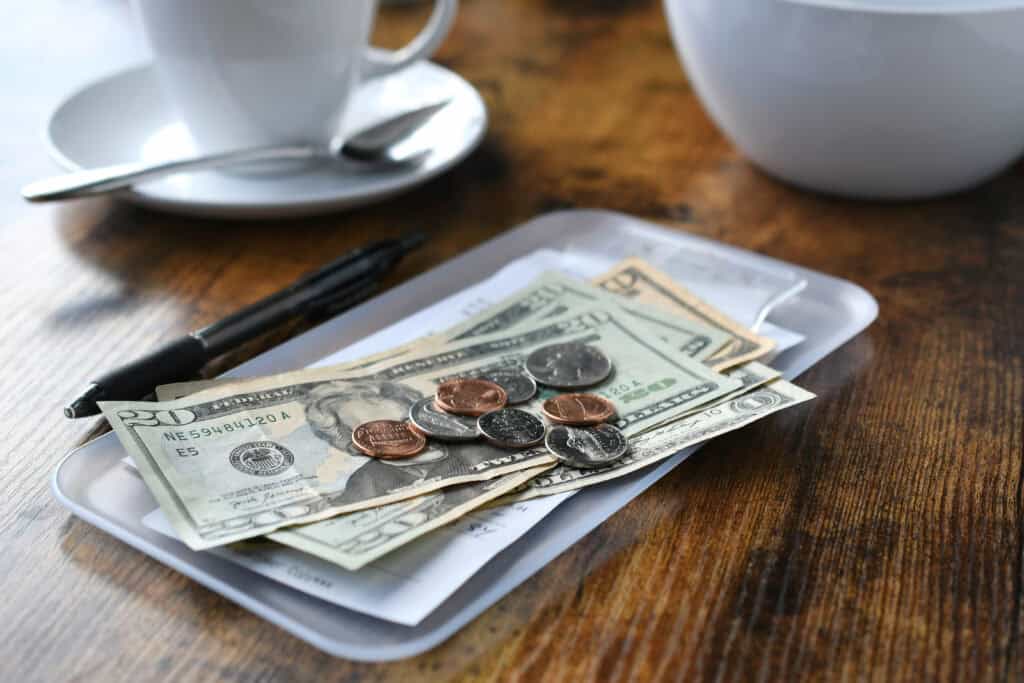 Cash tip left on receipt with coins and dollar bills in a restaurant