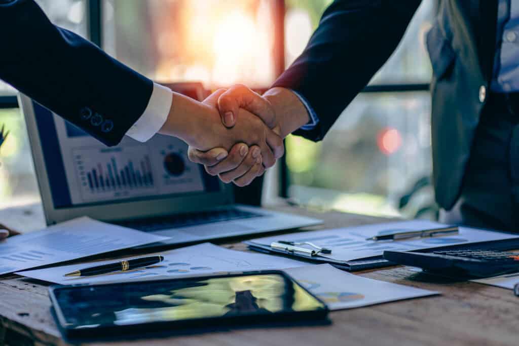Handshake between professionals across desk with financial documents